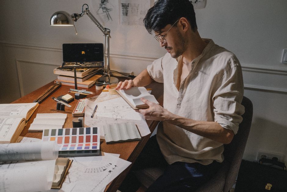 An architect examining blueprints and swatches at a desk, showcasing creativity and precision in design.