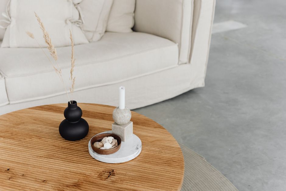 A stylish, minimalist living room setup featuring a candle, vase, and decorative shells on a wooden table.